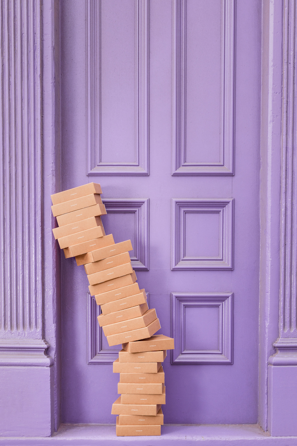 A towering stack of brown boxes outside of a purple door.