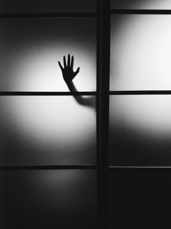 black and white photo of a hand pressed against a window pane