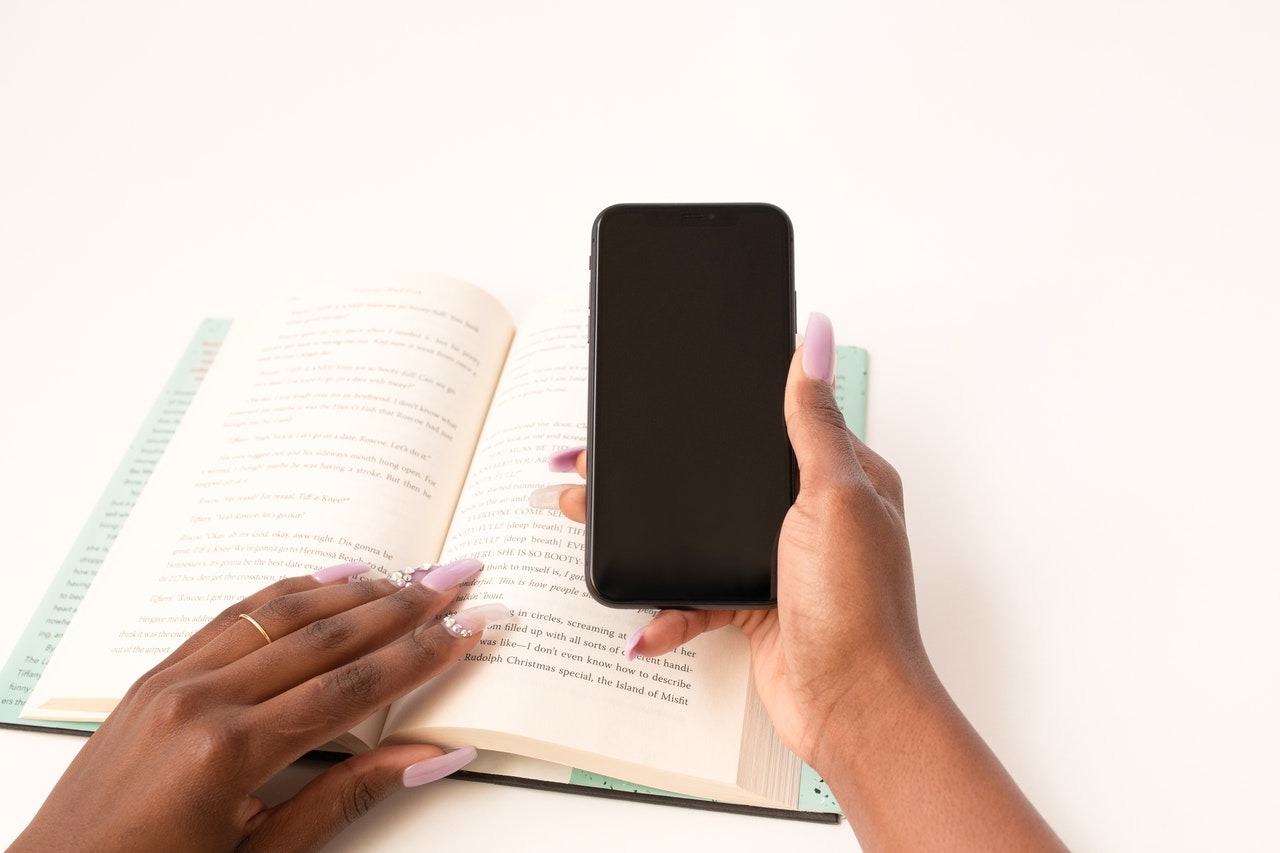 hands holding a phone over an open book