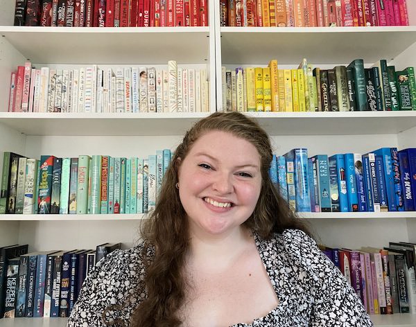 Smiling woman in front of color-coordinated bookshelves