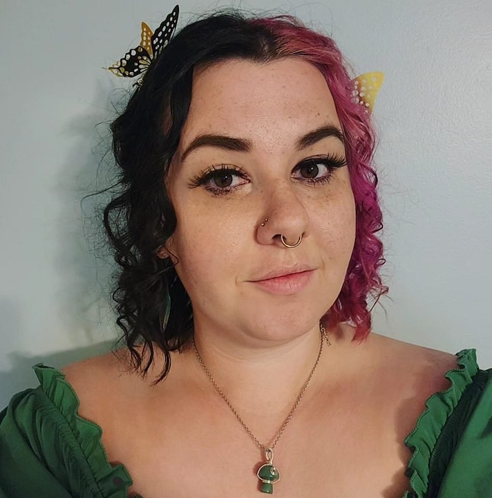 A headshot of a person with shoulder-length curly hair.